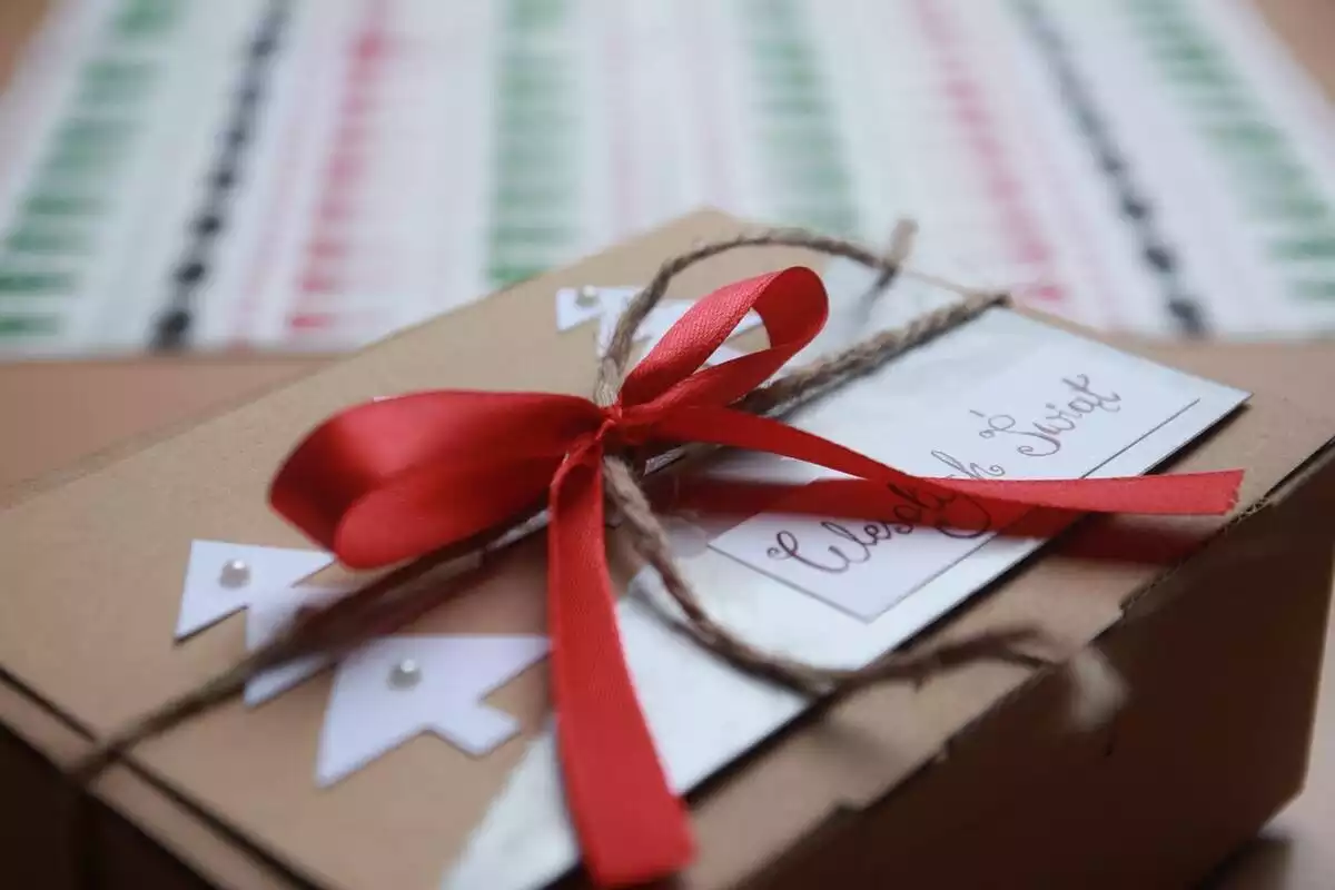 Un regalo de Navidad envuelto en una caja de cartón con un lazo rojo