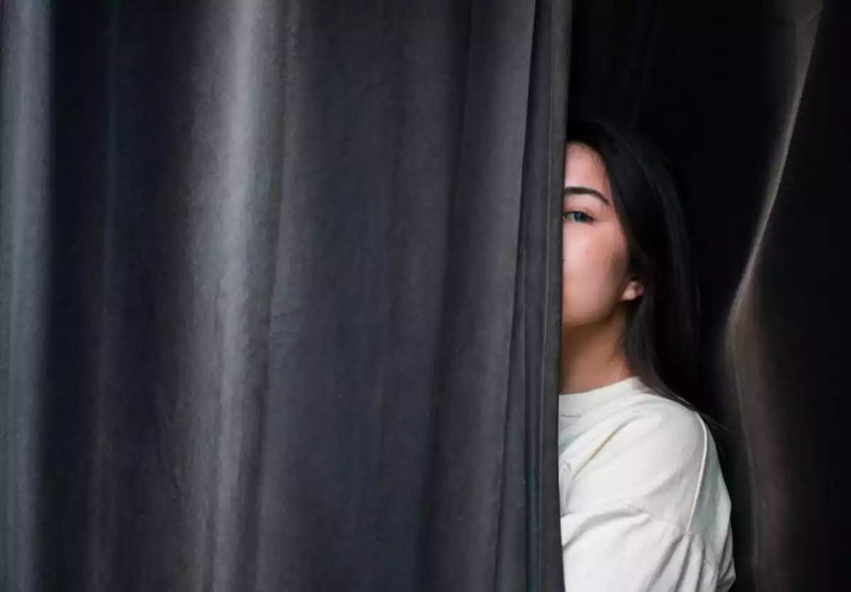Chica espiando detrás de la cortina