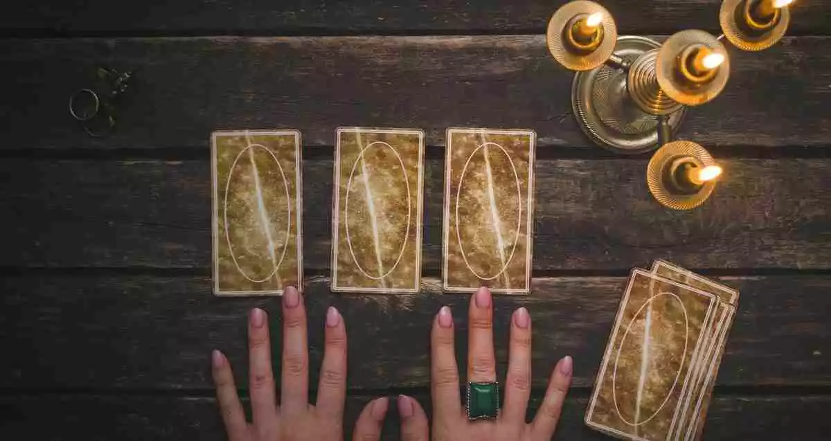 Tarot cards with a candle and some hands