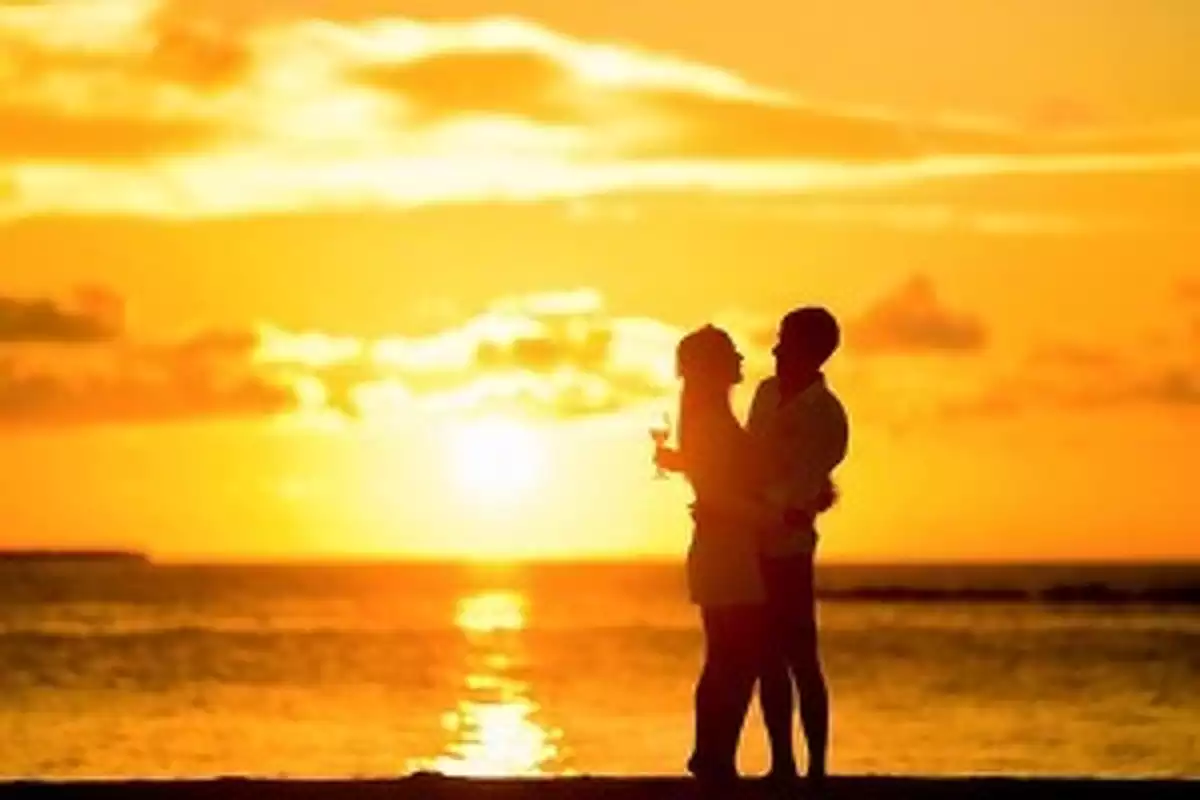 Couple entrelacé au coucher du soleil en bord de mer