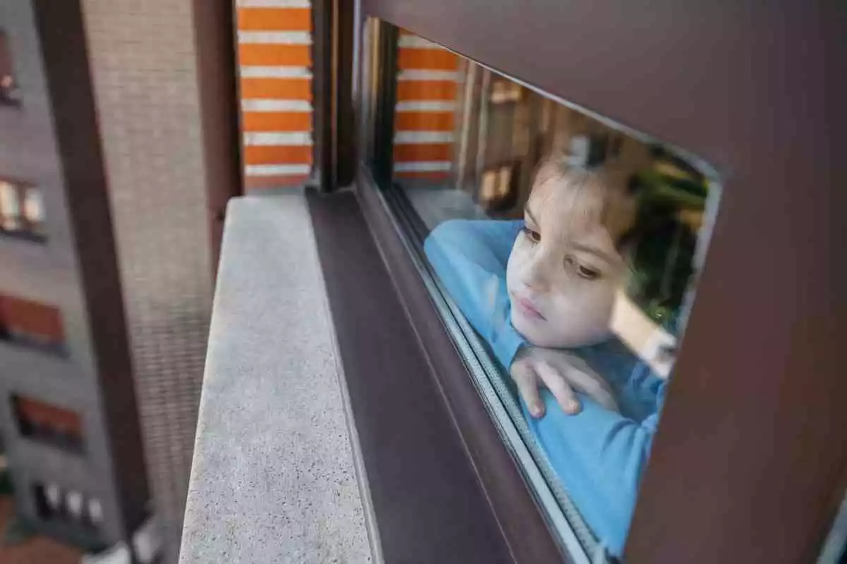 Une fille triste regarde par la fenêtre
