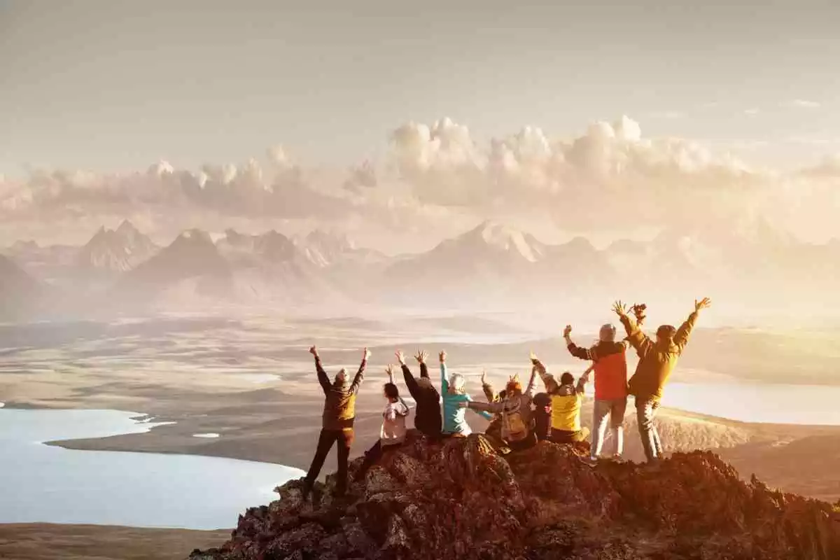 Un groupe de personnes levant les bras au sommet d'une montagne