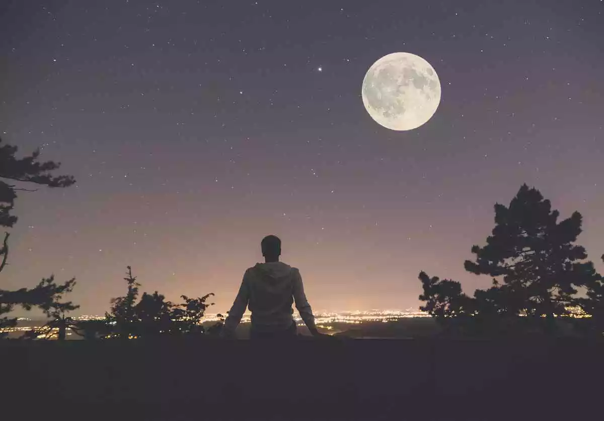 Photo d'un homme de dos devant une pleine lune