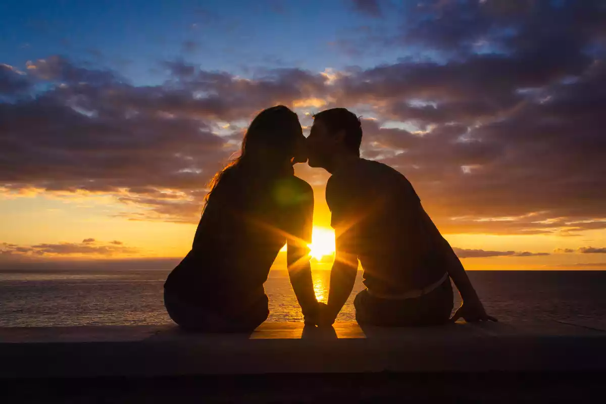 Couple s'embrassant devant un coucher de soleil