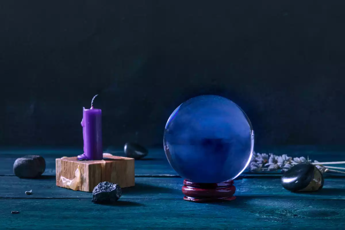 Une boule de cristal à côté d'une bougie lilas