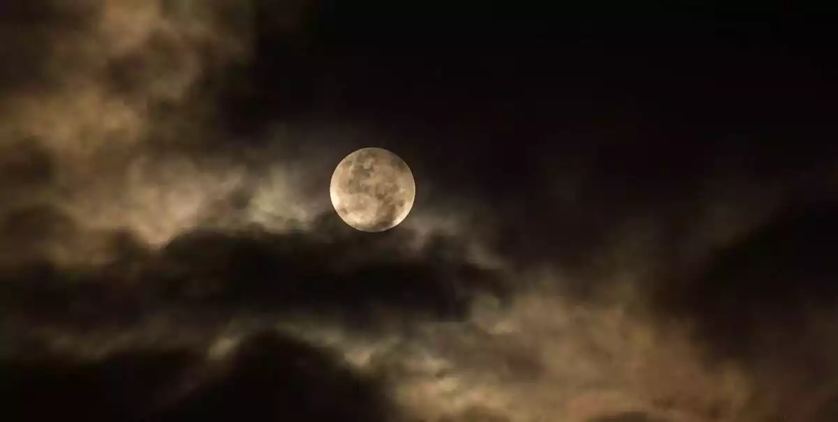 Photo d'une pleine lune derrière les nuages