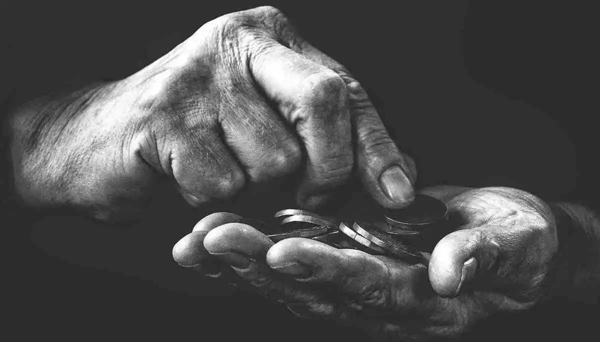 Photo en noir et blanc de mains contenant des pièces de monnaie