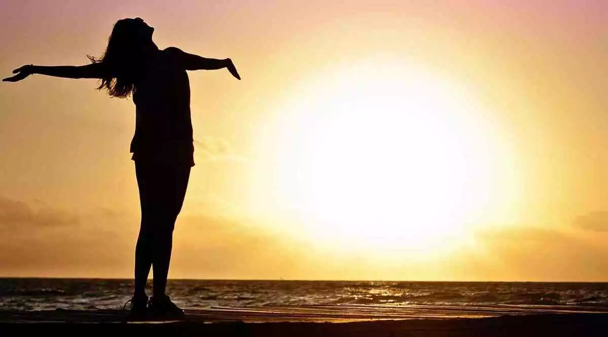 Photo d'une silhouette de femme à la plage lors d'un coucher de soleil