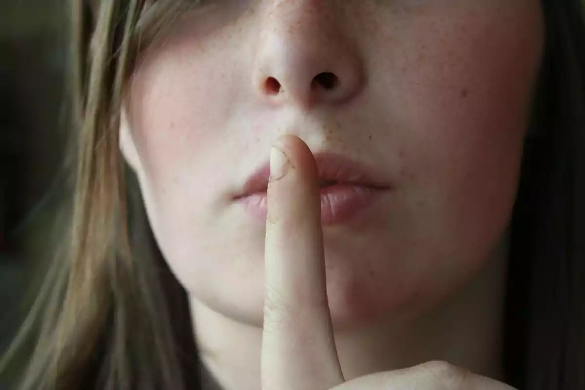 A woman with her finger in her mouth making the silence gesture