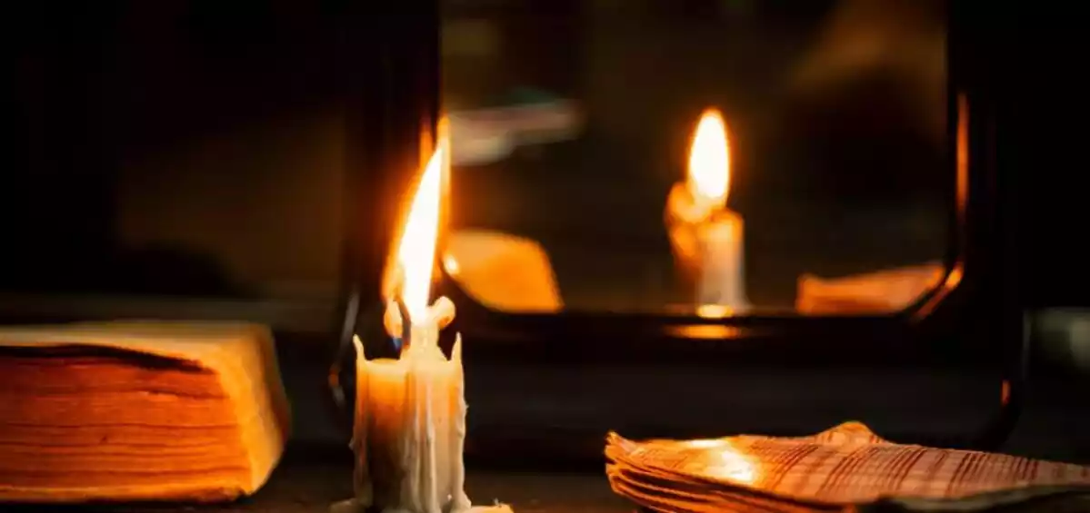 Candle in dark room in front of mirror