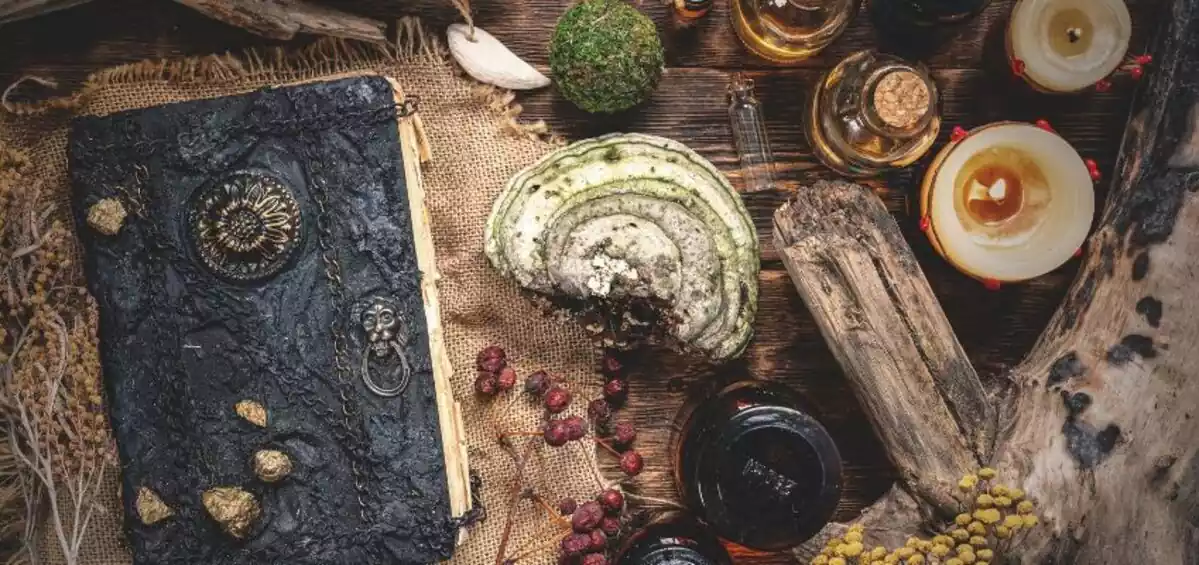 Old book on kitchen table next to mystery ingredients, candles and wood